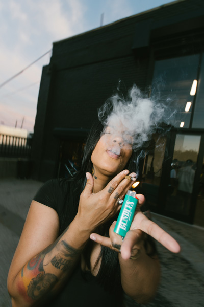 A person smoking a joint while holding a lighter